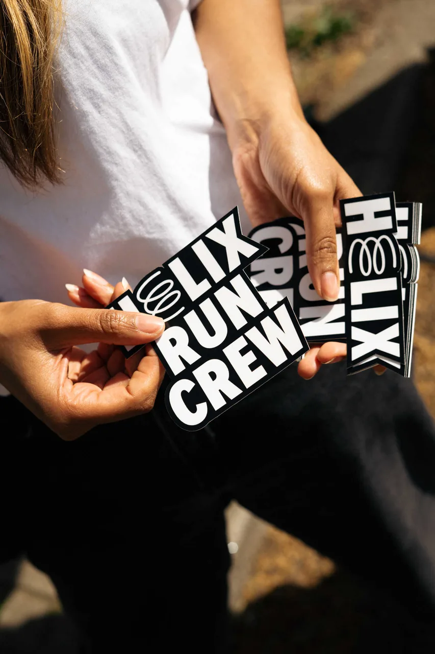 Hands holding a fan of Helix Run Crew stickers